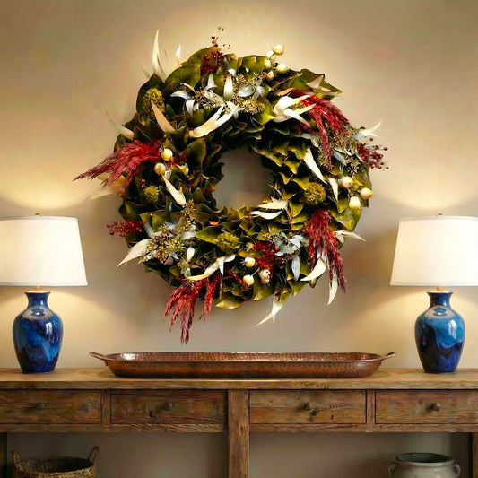 h potter woodland magnolia dried wreath on a wall above console table with 2 lamps