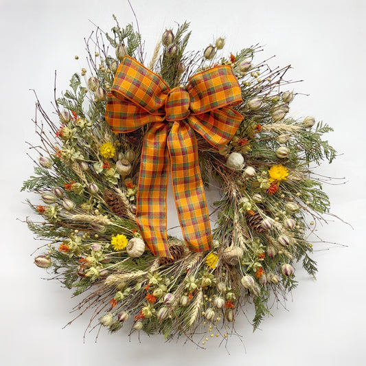 Autumn bramble wreath on wall with bow handmade H Potter dried botanicals: twigs, cedar, safflower, strawflower, pine cones.