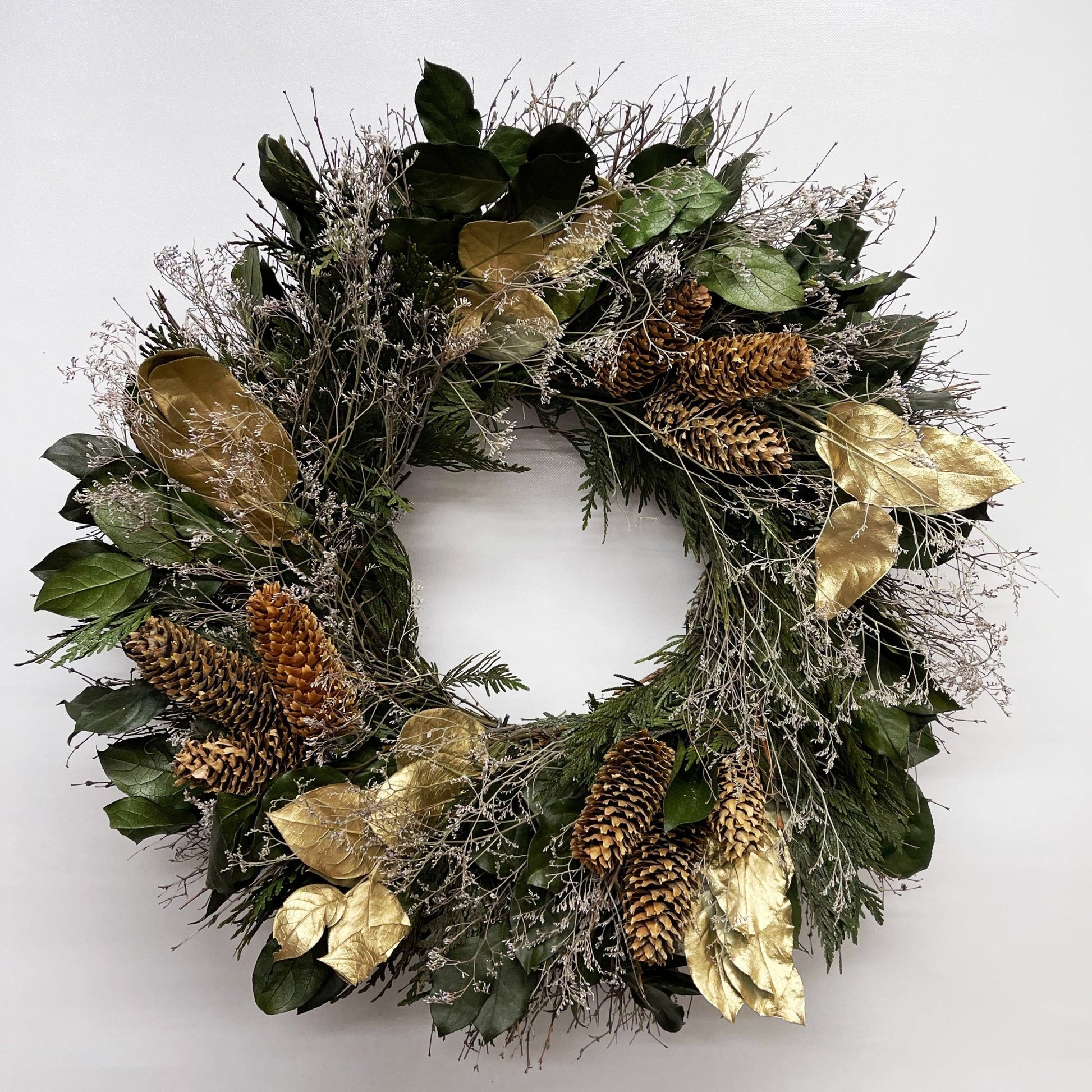 decorative christmas wreath with frosty accents gold leaves and pinecones on a white background