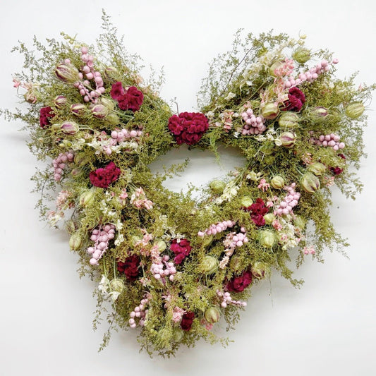 Heart-shaped Valentine's wreath with flowers and greenery on a white background