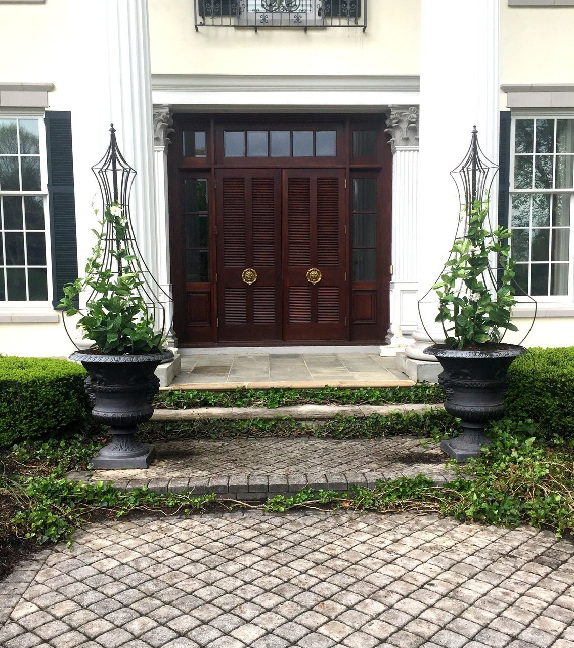 Pair of H Potter metal obelisk trellises in urns flanking an entry to a home at the front door, supporting climbing vines