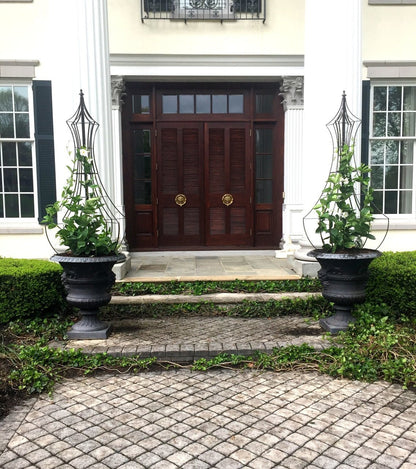 Pair of H Potter metal obelisk trellises in urns flanking an entry to a home at the front door, supporting climbing vines